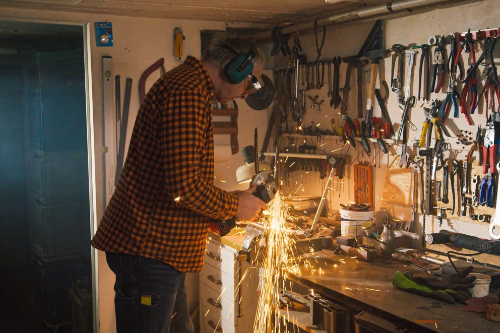
			Bernhard Wiemer flext in seiner Werkstatt an einem Rahmen.

		
