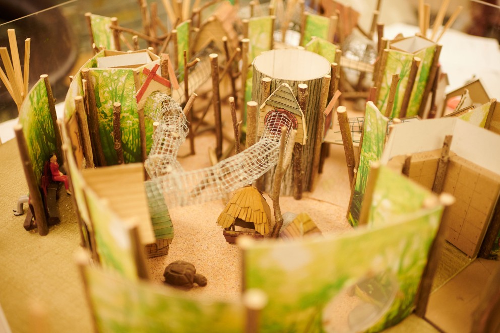 
			Das Modell eines Spielplatzes, gebaut aus Pappe, Draht und kleinen Ästen.

		