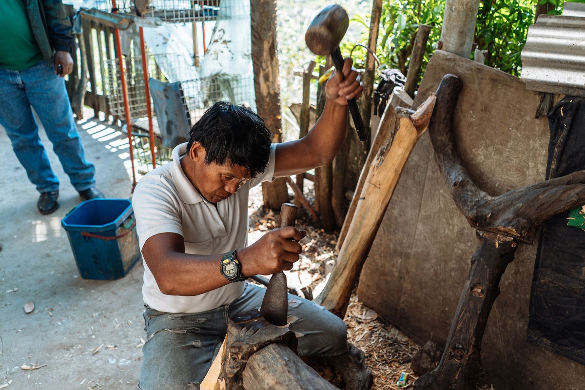 Jose Campol bearbeitet mit Hammer und Spachtel ein Stück Holz zu einem Holzroller 