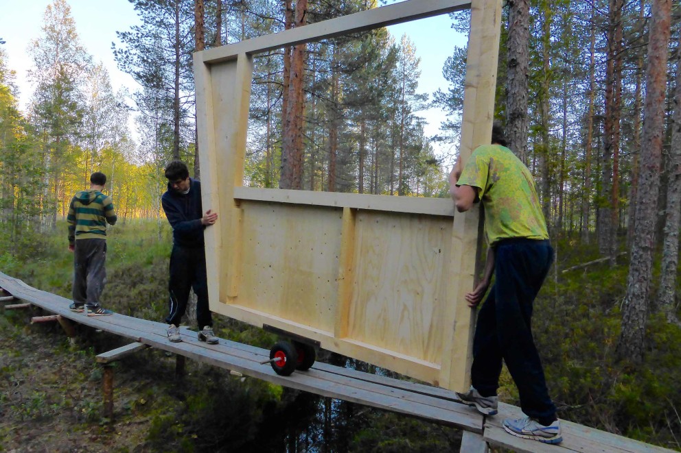 
			Über den 200 Meter langen Steg transportieren Timm und Jonas die Holzmodule zur Baustelle.

		