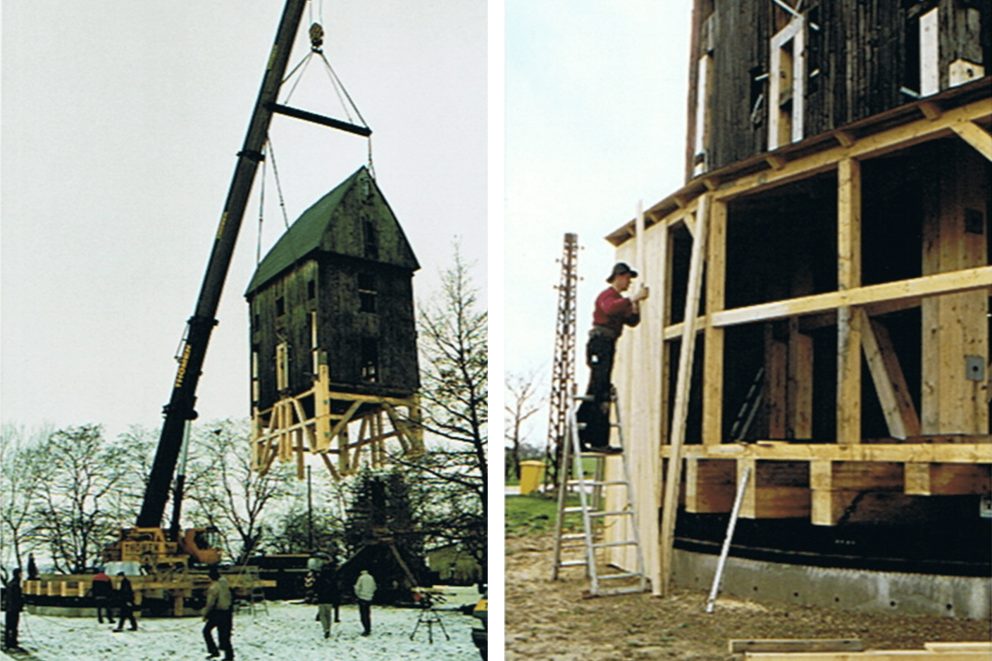 
			Die Bockwindmühle wird mit einem Kran auf die neue Position gestellt, sitzt auf dem Rollenkranz. Martin verkleidet dann das neue Stockwerk mit Holzbrettern.

		