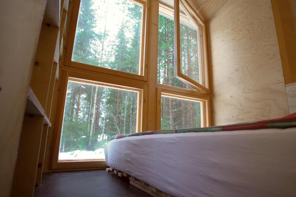 
			Das Schlafzimmer mit Blick in den Wald ist schlicht gehalten.

		