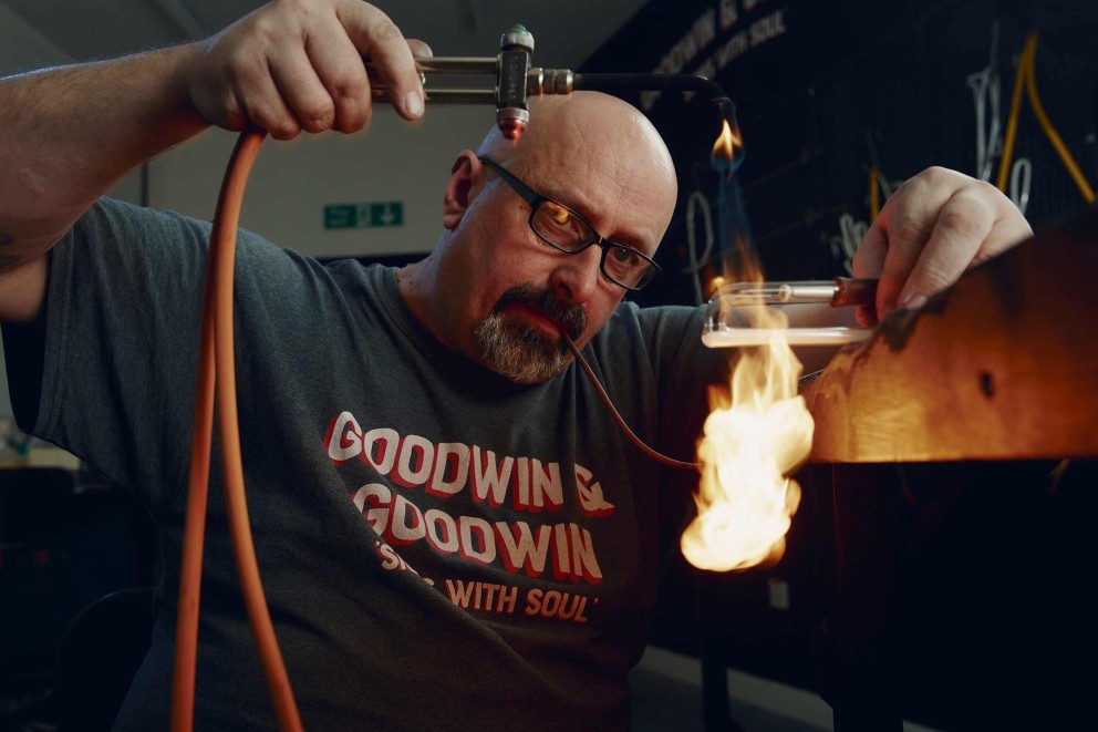 
			Perfektes Multitasking: Neonlicht Hersteller Paul Charlton brennt das Glas, formt es und pustet Luft hinein. Jeder Glasbläser entwickelt dabei seinen eigenen Stil.

		