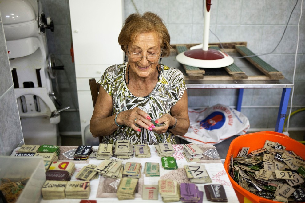 
			Eine ältere Dame zählt die Essensmarken im selbstgebauten Freizeitpark von Bruno Ferrin;

		