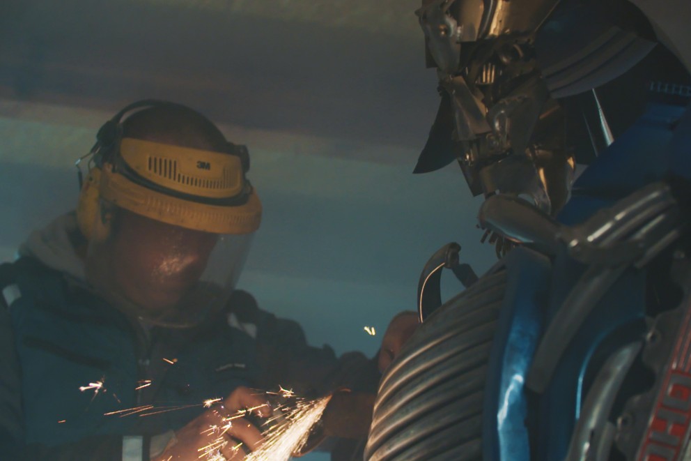 
			Sebastian Kucherski flext an einem Stück Metall des Roboters Optimus Prime

		