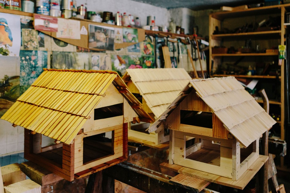 
			Drei Miniatur Holzhäuser im Rohbau mit Dächern.

		