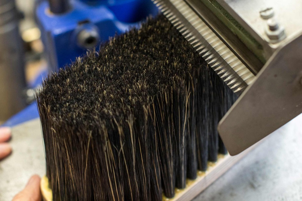 
			Alle Borsten werden mit einer Art Rasierapparat auf die gleiche Länge geschnitten. Diese Bürsten stellt Pinselmacherin Sybille Großmann in ihrer Werkstatt in Ravensburg her.

		