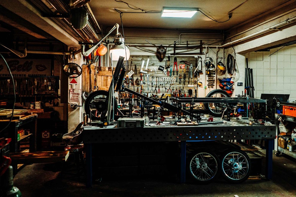 
				Tills Werkstatt mit einem Lastenrad auf der Werkbank.

			