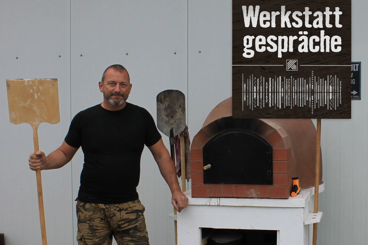 Christian Staffler steht neben seinem selbstgebauten Pizzaofen aus selbstgemachten Tonziegeln und Europaletten. 