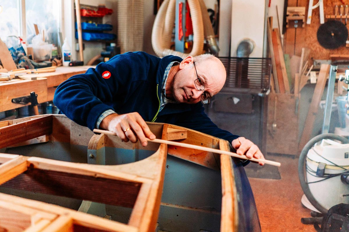 Heiner Haass misst eine Länge an seinem Boot in seiner Werkstatt. 