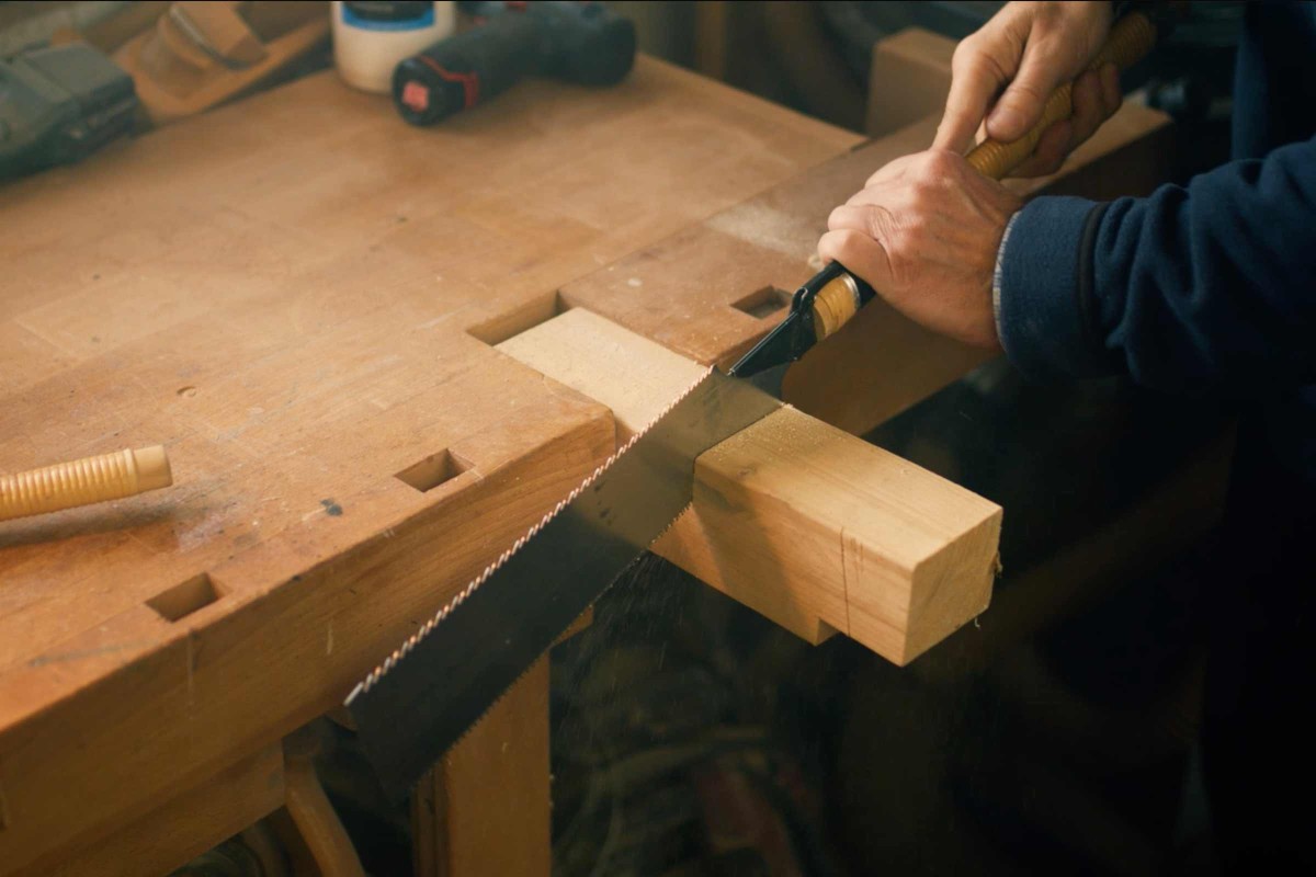 Heiner zersägt ein Stück Holz mit einer Japansäge. 